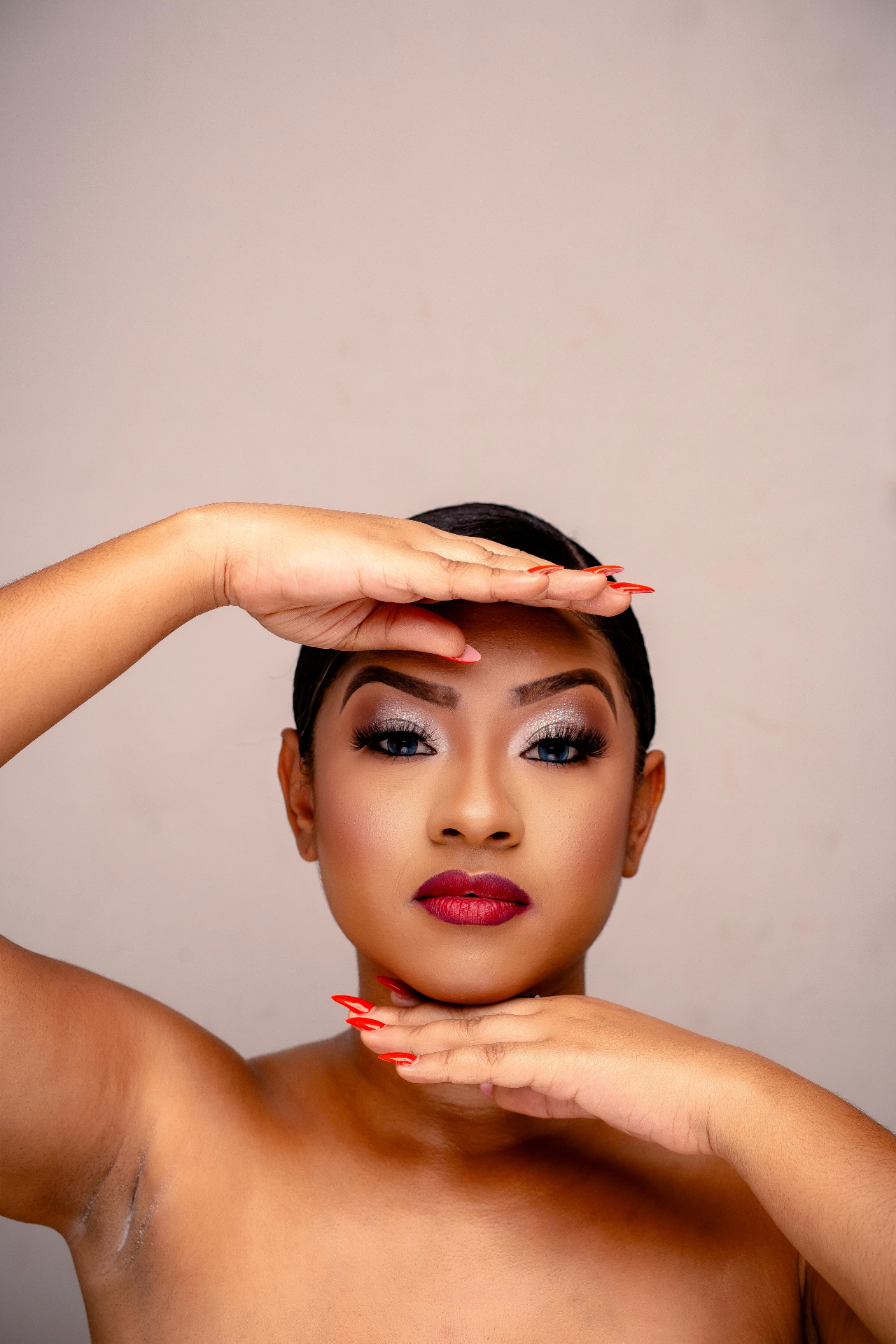 Beauty portrait with shimmer eyeshadow and red lipstick, hands framing the face