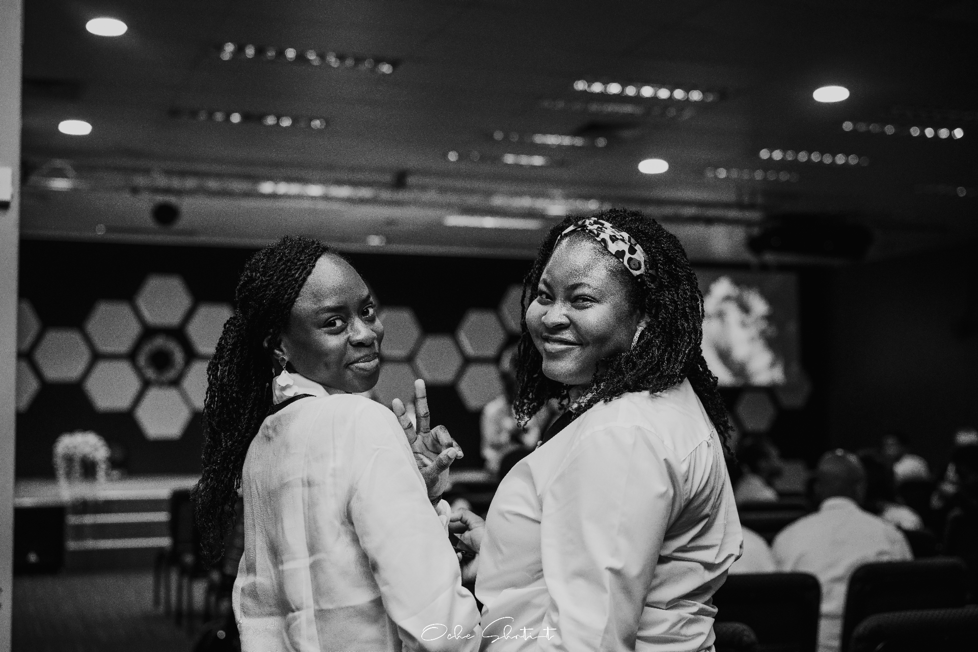 Two friends turning back with peace signs at a conference, black and white