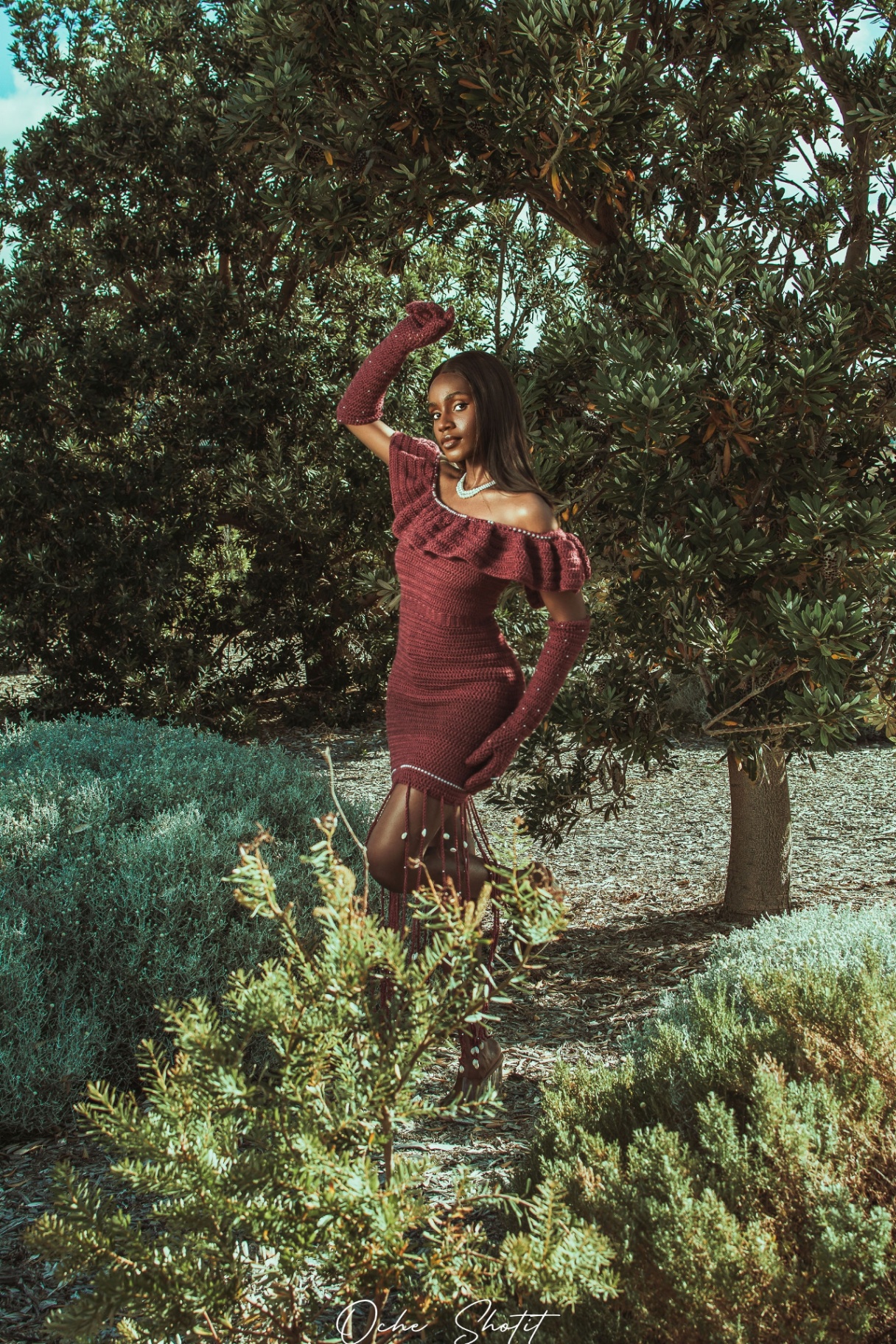 Fashion portrait in burgundy crochet dress amongst olive trees
