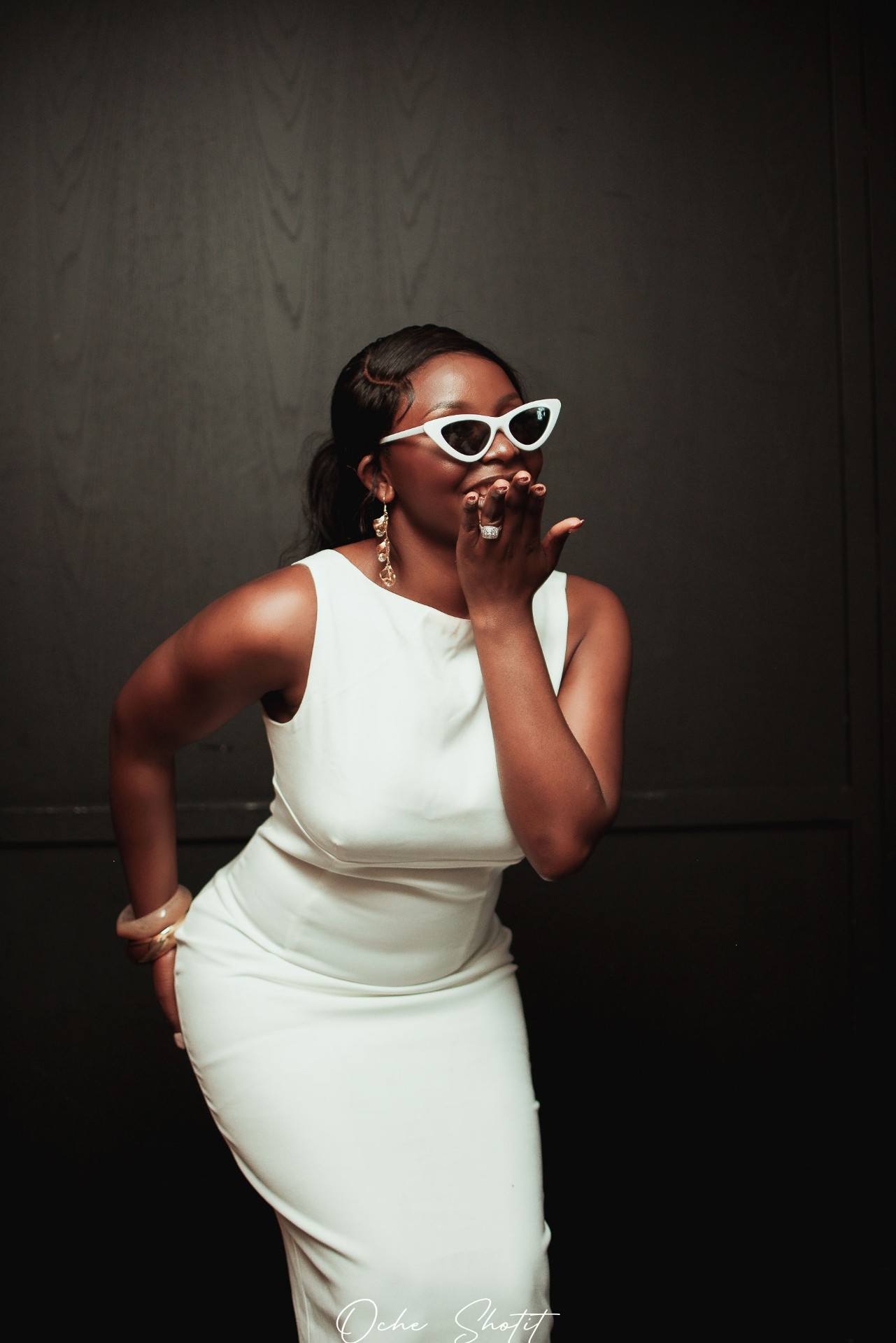 Portrait in white dress with cat-eye sunglasses, blowing a kiss