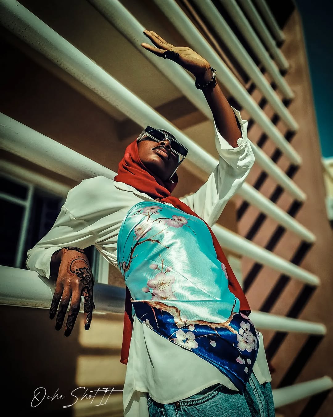 Street style portrait in white shirt and printed hijab with henna-decorated hand