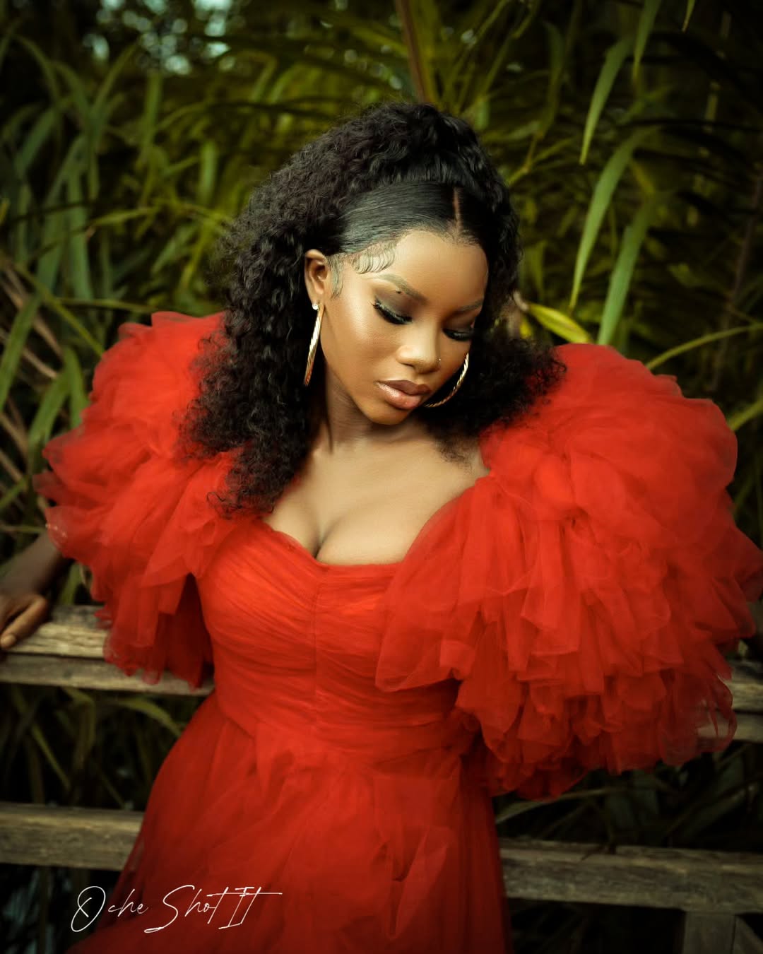 Editorial portrait in a dramatic red ruffled tulle gown against tropical greenery