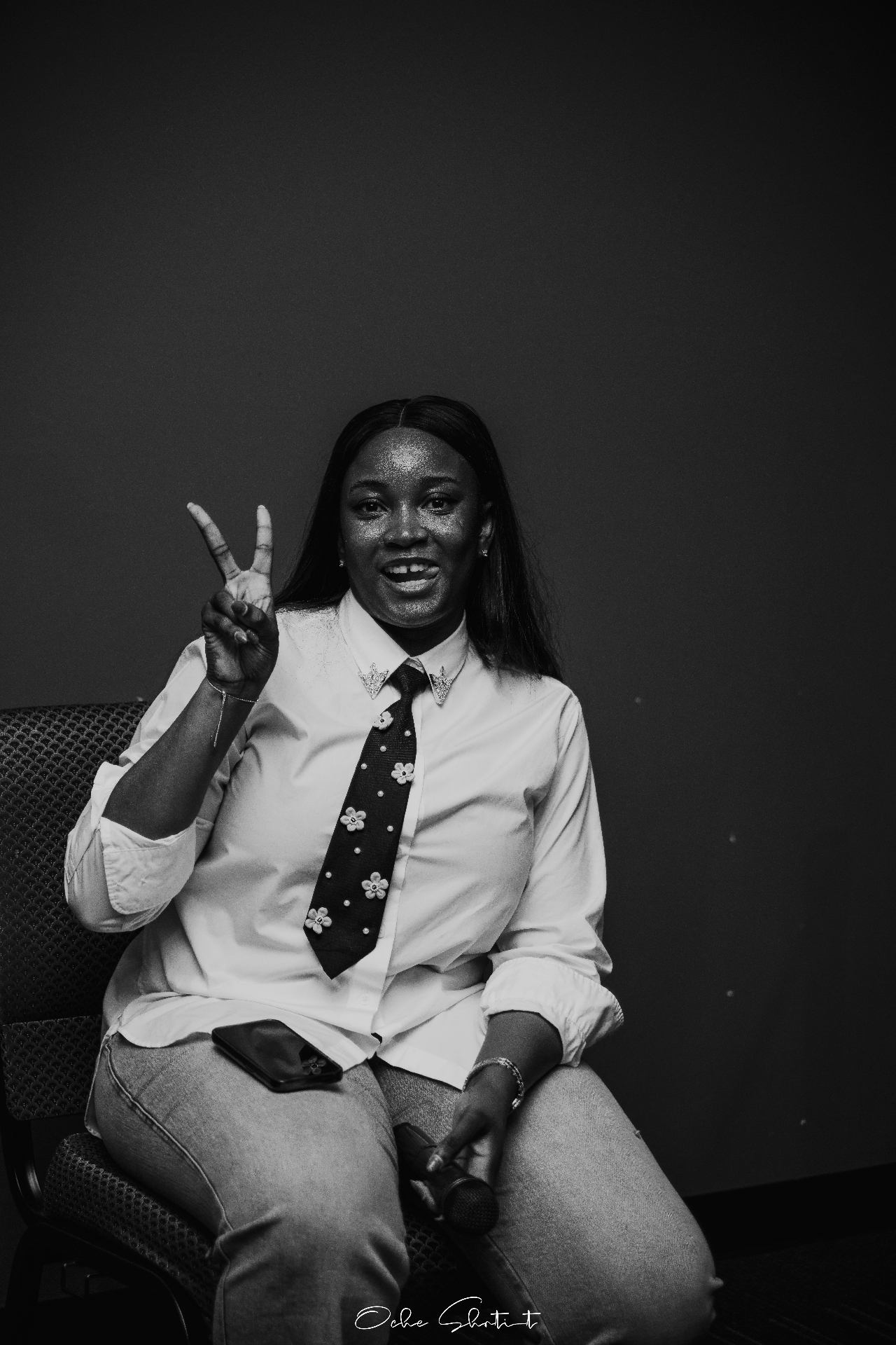 Seated portrait flashing a peace sign at an event, black and white