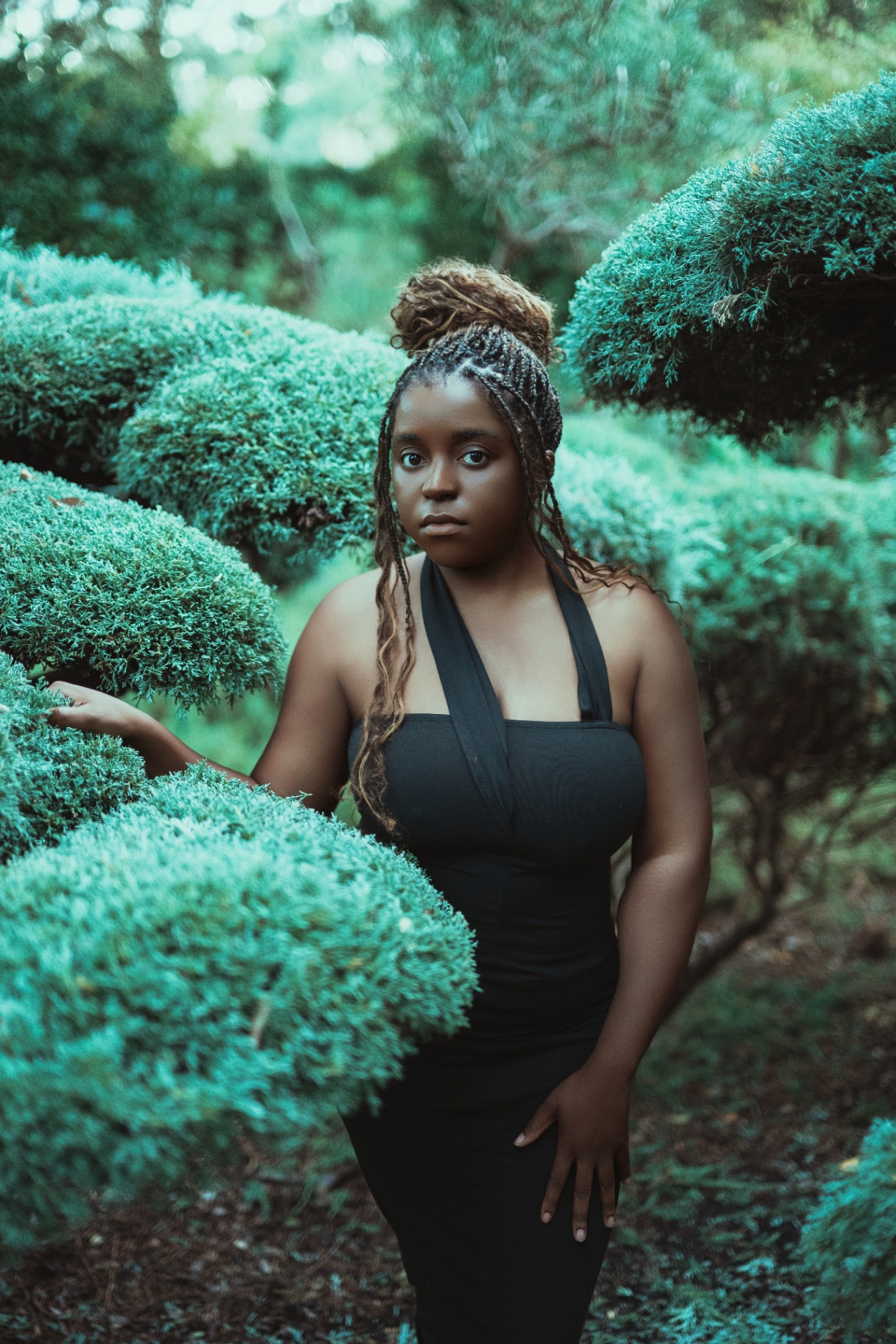 Portrait in a teal garden of sculpted shrubs