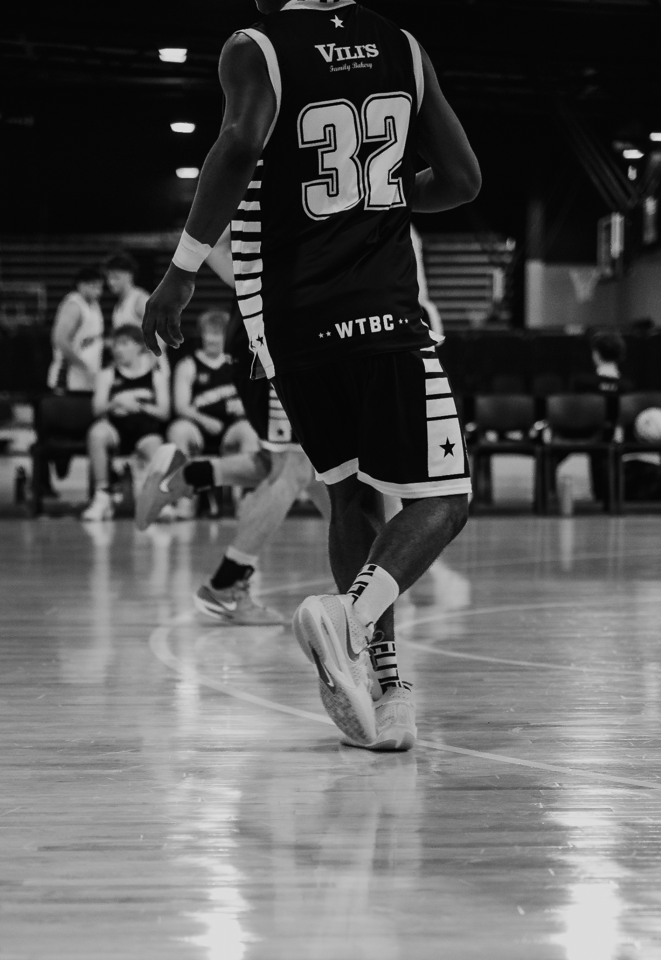 Basketball player #32 dribbling on the court, black and white