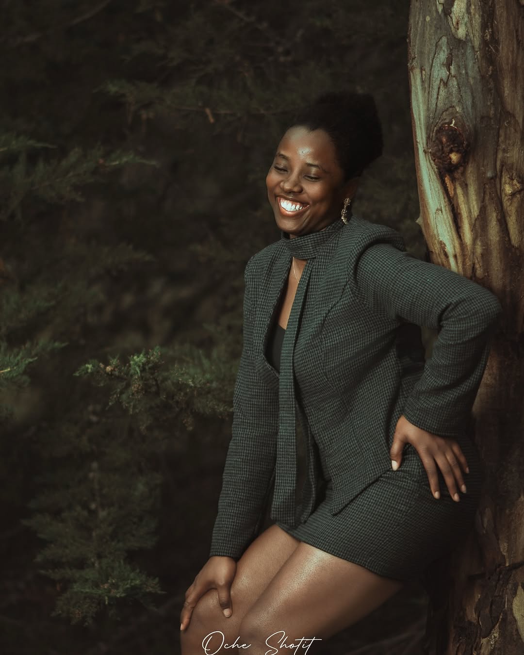 Joyful portrait in green tweed suit leaning against a tree in the forest
