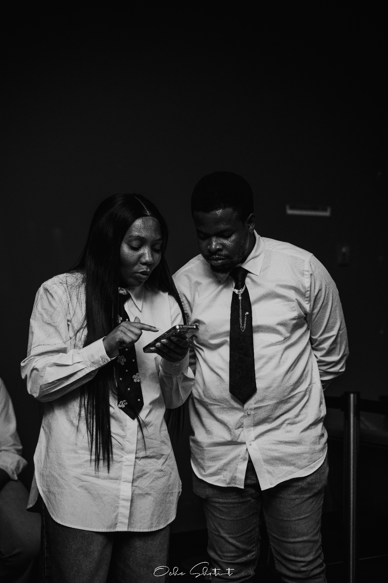Pair reviewing a phone backstage at an event, black and white